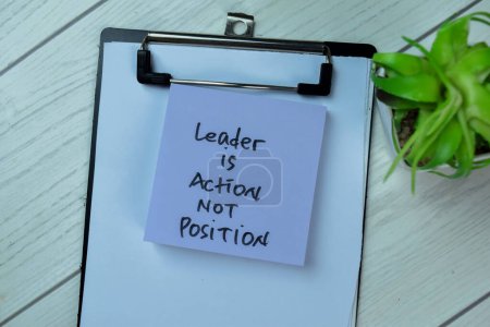 Photo for Concept of Leader is Action Not Position write on sticky notes isolated on Wooden Table. - Royalty Free Image