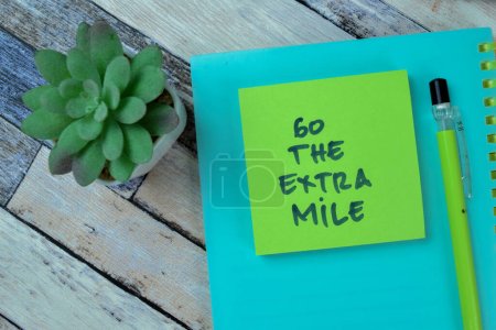 Téléchargez les photos : Concept de Go The Extra Mile écrire sur des notes collantes isolées sur une table en bois. - en image libre de droit