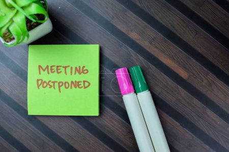 Photo for Concept of Meeting Postponed write on sticky notes isolated on Wooden Table. - Royalty Free Image