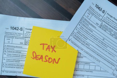 Concept of Tax Season write on sticky notes isolated on Wooden Table.