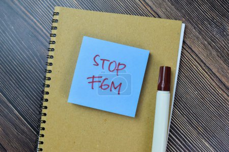 Téléchargez les photos : Concept de Stop FGM écrire sur des notes collantes isolées sur la table en bois. - en image libre de droit