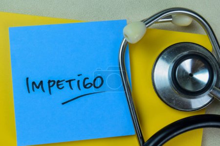 Photo for Concept of Impetigo write on sticky notes with stethoscope isolated on Wooden Table. - Royalty Free Image