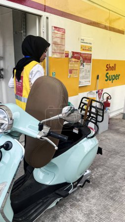 Téléchargez les photos : Les travailleurs des stations-service servent les clients en remplissant l'essence à l'aide d'une pompe à essence dans la moto de l'acheteur. Bekasi, Indonésie, 5 décembre 2023 - en image libre de droit