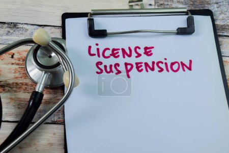 Photo for Concept of License Suspension write on paperwork with stethoscope isolated on wooden background. - Royalty Free Image