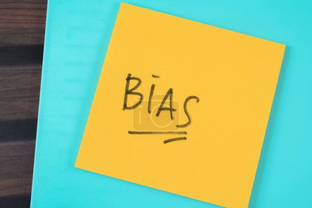 Concept of BIAS write on sticky notes isolated on Wooden Table.