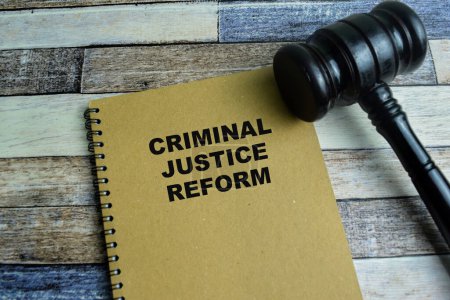 Concepto de Reforma de la Justicia Penal escribir en libro con mazo aislado en mesa de madera.