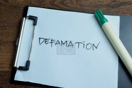 Concept of Defamation write on paperwork isolated on wooden background.