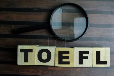 Konzept der Holzwürfel mit dem Wort TOEFL auf Holzgrund.