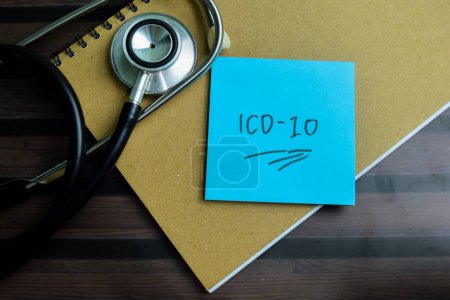 Concept of ICD-10 write on sticky notes with stethoscope isolated on Wooden Table.