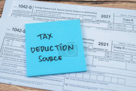 Concept of Tax Deduction Source write on sticky notes isolated on Wooden Table.