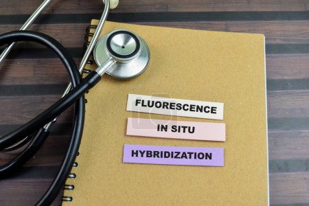 Konzept der Fluoreszenz bei Situ-Hybridisierung schreiben auf klebrige Notizen mit Stethoskop isoliert auf Holztisch.