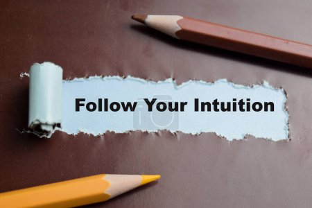 Concept of Follow Your Intuition Text written in torn paper.