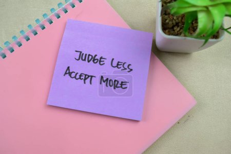 Concept of Judge Less Accept More write on sticky notes isolated on Wooden Table.