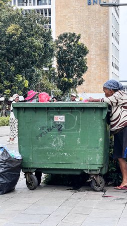 Photo for Woman collects garbage, cardboard and plastic to take it for processing and get money for food. Jakarta, Indonesia, May 1, 2024 - Royalty Free Image