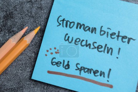 Concepto de Stromanbieter Wechseln - Geld Sparen escribir en notas adhesivas aisladas en la mesa de madera.