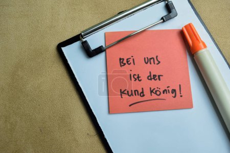 Concepto de Bei Uns Ist der Kund konig escribir en notas adhesivas aisladas en la mesa de madera.