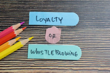 Concept of Loyalty or Whistleblowing write on sticky notes isolated on Wooden Table.