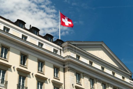 Foto de Ginebra, Suiza. 13 de agosto. 2023. La bandera nacional suiza ondeando al viento en un edificio en el distrito de Lake Geneva. - Imagen libre de derechos