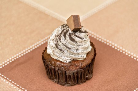 Téléchargez les photos : Petit gâteau bruni avec crème à fouetter et morceau de chocolat sur le dessus. - en image libre de droit