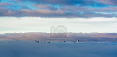 Photo for Sunrise view at high-rise Metrotown towers covered with the fog on cloudy sky background - Royalty Free Image