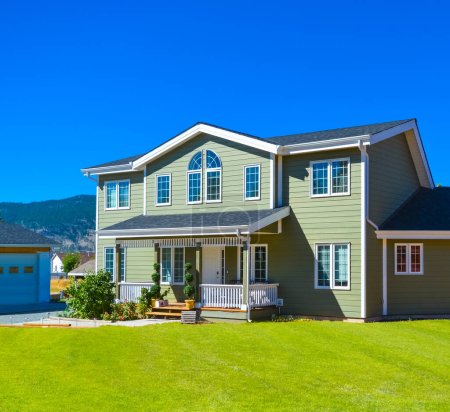 Gran casa familiar con camino a la puerta en frente y fondo azul cielo. Columbia Británica, Canadá.