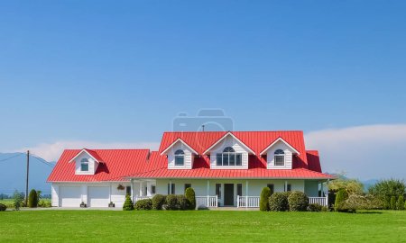 Farmers family house with double garage green lawn in front and blue sky background. British Columbia, Canada
