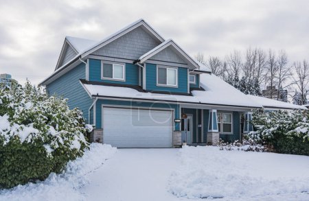 Family house with front yard in snow. Residential house on winter cloudy day