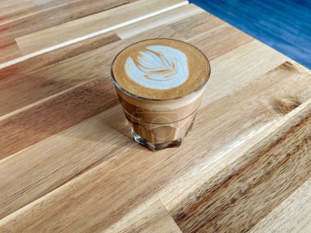 Un vaso de café con leche sobre la textura de madera de la mesa.