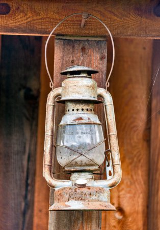 Alte rostige Öllampe unter dem sommerlichen Holzschuppen.