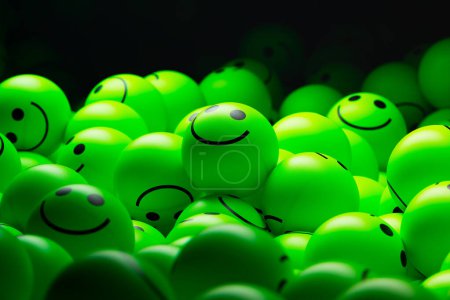 Foto de Representación en 3D de una gran pila de pequeñas bolas verdes de neón. Cada bola tiene una cara sonriente pintada en ella, creando una escena alegre y lúdica. - Imagen libre de derechos