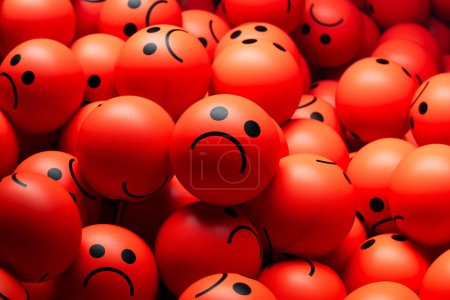 Téléchargez les photos : Un gros tas de boules rouges avec des expressions tristes ou en colère. Pile de boules colorées avec des visages tristes ou en colère, transmettant des émotions telles que la dépression, la tristesse, la colère, le stress et le désespoir. - en image libre de droit