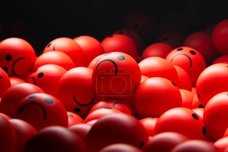 Foto de Una gran pila de bolas rojas con expresiones tristes o enojadas. Montón de bolas coloridas con caras tristes o enojadas, que transmiten emociones como depresión, tristeza, ira, estrés y desesperanza. - Imagen libre de derechos