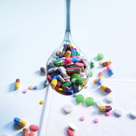 Photo for A collection of multicolored pills, capsules, and tablets arranged neatly on a white spoon. This image is perfect for backgrounds related to medicine, healthcare, or pharmacy - Royalty Free Image