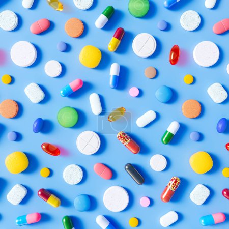 Foto de Innumerables píldoras, cápsulas y tabletas multicolores están dispersas sobre un fondo azul claro. Esta foto es perfecta para su uso en medicina, farmacia o temas de salud. - Imagen libre de derechos