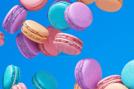 Photo for Falling down macarons. Delicious french almond cookies on a blue background. Gift for Valentine's Day, Mother Day. Sweet dessert in blue, pink, purple pastel colours. Tasty bakery. Food - Royalty Free Image