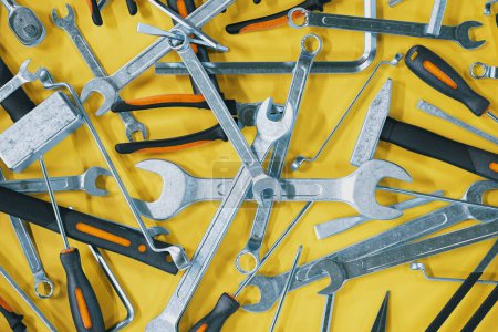 Beaucoup d'outils d'atelier sont répartis sur la surface jaune. Marteaux, tournevis, clés, clés, pinces, clés torx et hexagonales. Rénovations. Entretien mécanique. Boîte à outils essentiels.