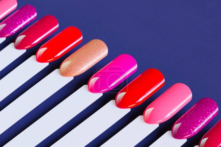 Photo for Nail polish swatches in different colors. Colorful manicure lacquer samples arranged on a blue background. Multicolor vibrant set of false nails for beauty salon. Choice for the client. - Royalty Free Image