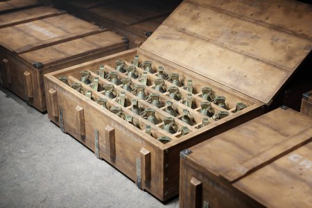 Wooden military boxes filled with grenades. The ammunition containers are shown stacked one next to another, with each box containing a significant number of grenades. A dark and gritty atmosphere.