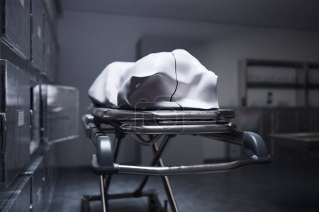 Foto de Una imagen muestra el cadáver cubierto con un paño blanco en la morgue. Esperando el funeral o la disección. La habitación está equipada con refrigeradores mortuorios, donde los restos humanos se enfrían - Imagen libre de derechos