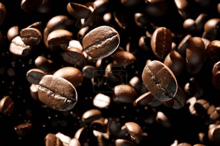 Foto de Arábica tostada marrón o granos de café Robusta cayendo sobre un fondo oscuro. La imagen muestra la caída de granos de café fresco, que representa el desayuno, la energía, la cafeína y el aroma - Imagen libre de derechos
