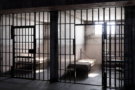 In einer trostlosen Gefängniszelle strömen die Sonnenstrahlen durch das offene Fenster und werfen einen warmen und strahlenden Schein auf das Bett. Dieses Bild fängt das Nebeneinander von Freiheit und Enge ein.