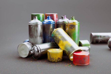 Foto de Múltiples latas de pintura en aerosol de colores en una pila sobre un fondo gris. Una colección de pintura acrílica colorida en aerosol, perfecta para proyectos creativos, temas artísticos, proyectos de bricolaje y arte urbano - Imagen libre de derechos