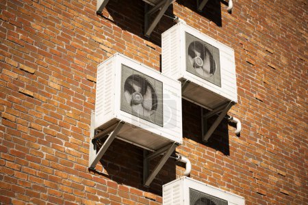 Téléchargez les photos : Climatiseur extérieur sur le mur de briques. L'équipement de ventilation refroidit l'air chaud pour un climat parfait et sain. Technologie moderne, efficacité énergétique et système de refroidissement supérieur. - en image libre de droit