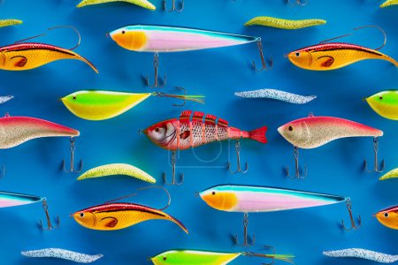 Foto de Una fila de diversas picaduras de peces de colores. Conjunto de señuelos multicolores y anzuelos para el hobby de la pesca. Se encarga de atrapar un pez. Equipo de pesca en un fondo azul. Wobblers. entusiastas de la pesca - Imagen libre de derechos