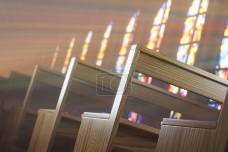 Foto de Una capilla vacía con filas de bancos de madera bañados por la cálida luz del sol que fluye a través de vidrieras. Los vibrantes rayos divinos crean un sentido de significado religioso y espiritual - Imagen libre de derechos