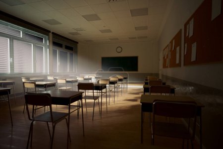 Photo for Rays of light falling to the empty dark classroom. Teaching class without students during a break. Abandoned school. Disturbing mood. The essence of abandonment and the fleeting nature of knowledge. - Royalty Free Image