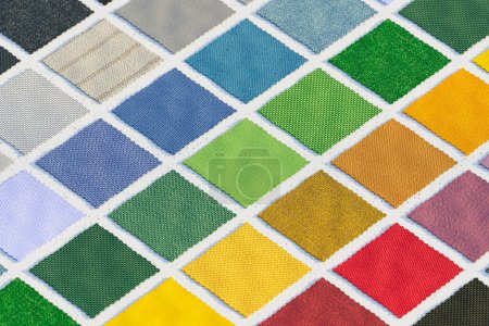 Un étalage organisé d'échantillons de tissu dans différentes nuances disposées dans le sens de la couleur sur une planche. Parfait pour les designers ou les décorateurs à la recherche d'inspiration couleur.