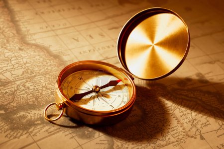 Photo for Close-up view of a vintage gold compass lying on an old, weathered map.This serves as a vital guide for adventurers embarking on their unknown ventures across uncharted territories. - Royalty Free Image