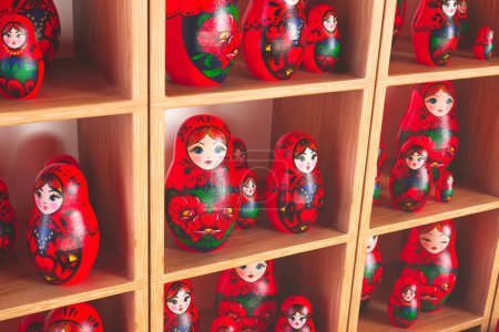 Una amplia gama de muñecas rusas nido Matryoshka vívidamente pintadas, cada una mostrando diseños florales ornamentados y patrones tradicionales, encaramadas en estantes de madera.