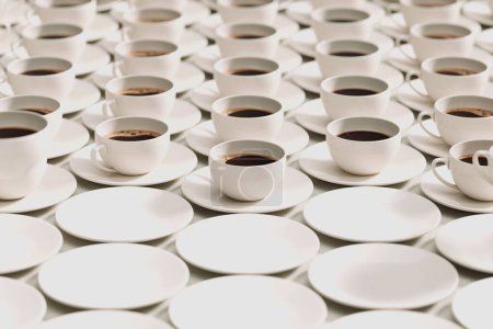 Overlooking a striking, neatly organized pattern, white coffee cups filled with black coffee are symmetrically aligned on a textured surface, ideal for cafe and catering settings.